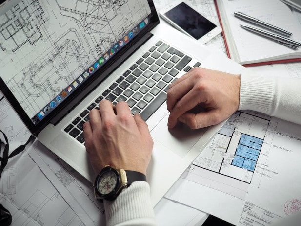 A architect using a laptop to plan out their construction project and researching into an installer for their high-voltage electrical distribution for the build.